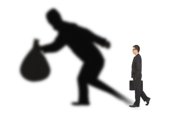 businessman walking and holding bag  with thief shadow